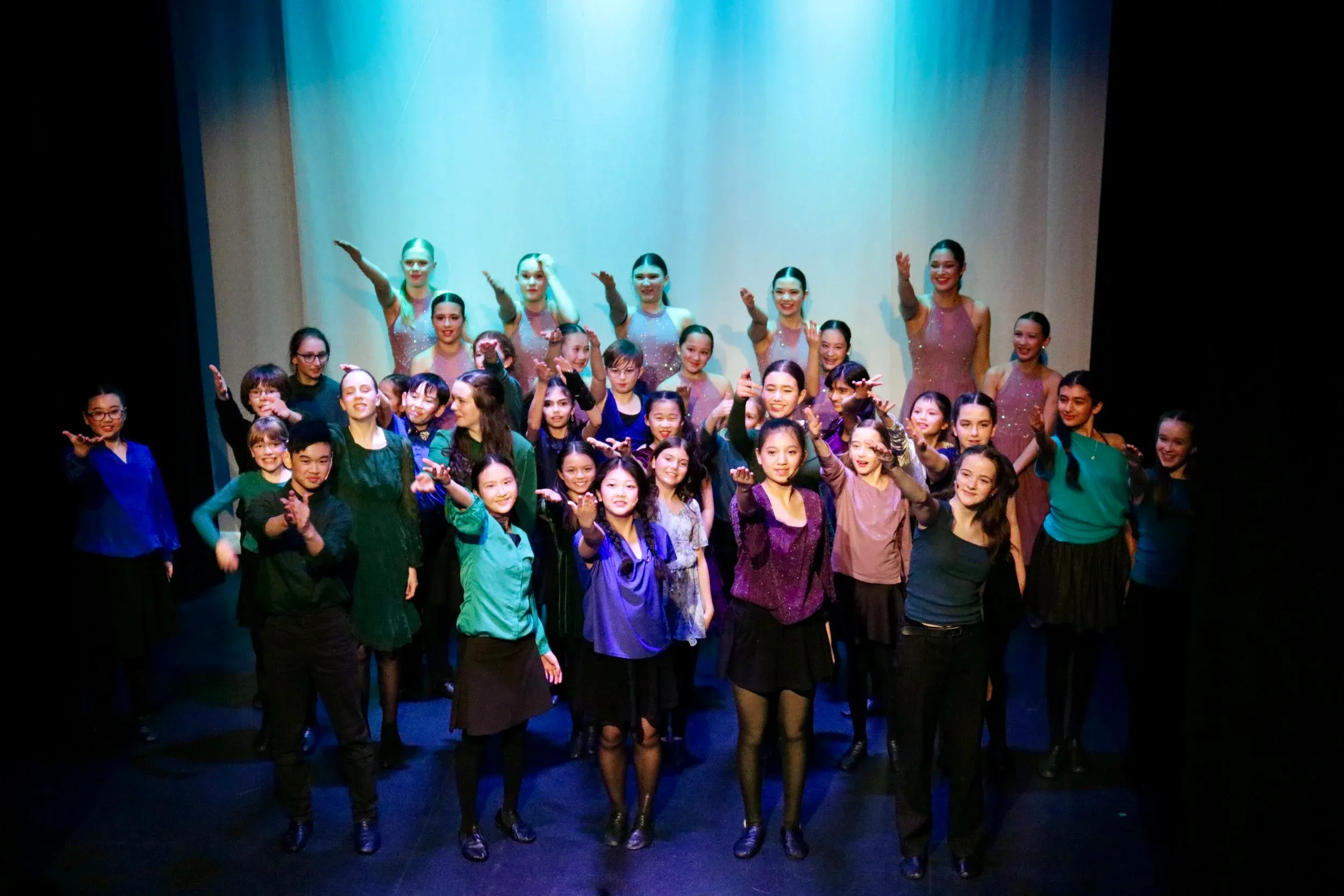 Large VPS ensemble cast on stage taking a bow together under blue stage lighting