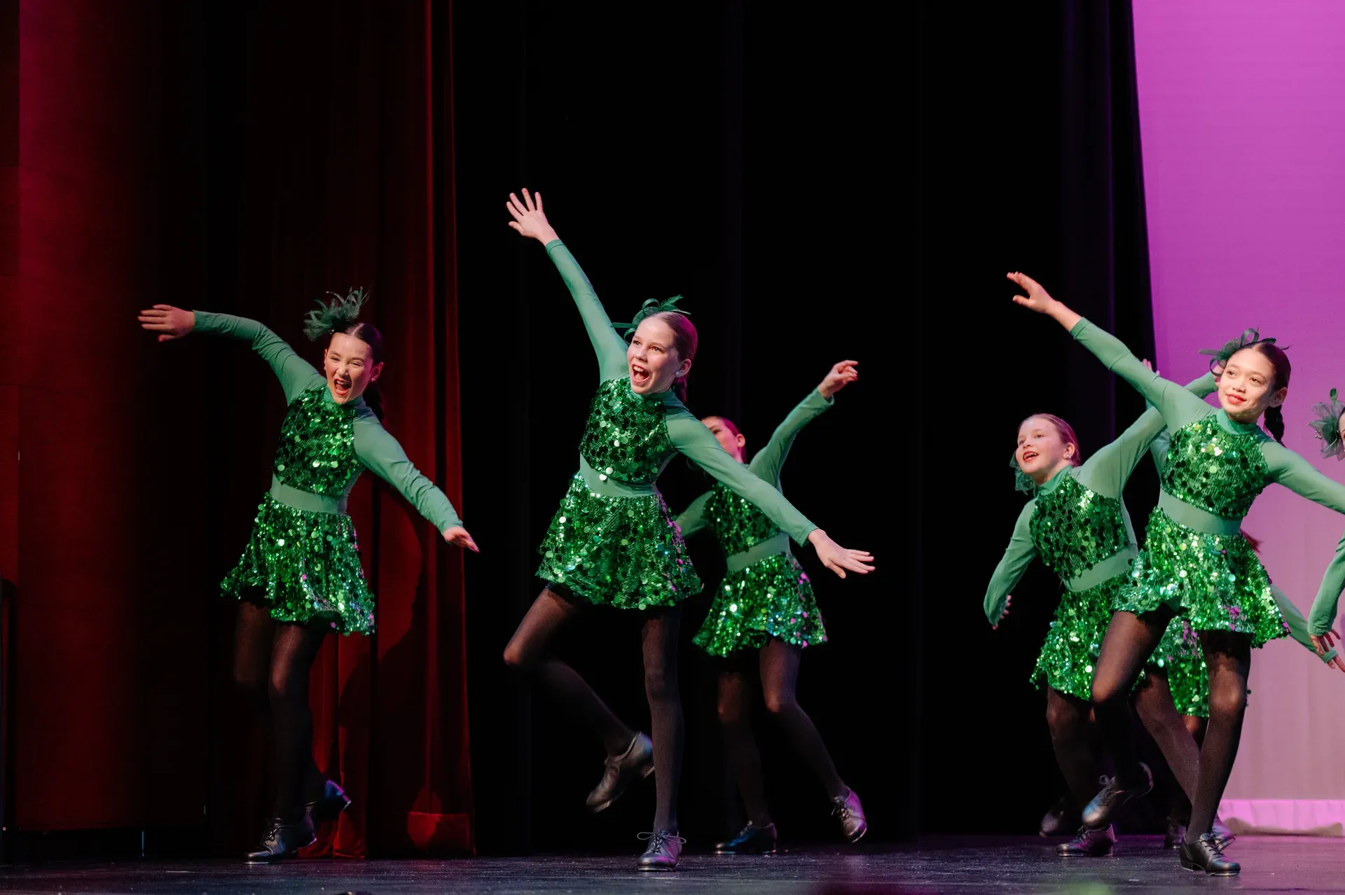 VPS jazz and tap dancers performing on stage in green sequin costumes, arms raised and smiling