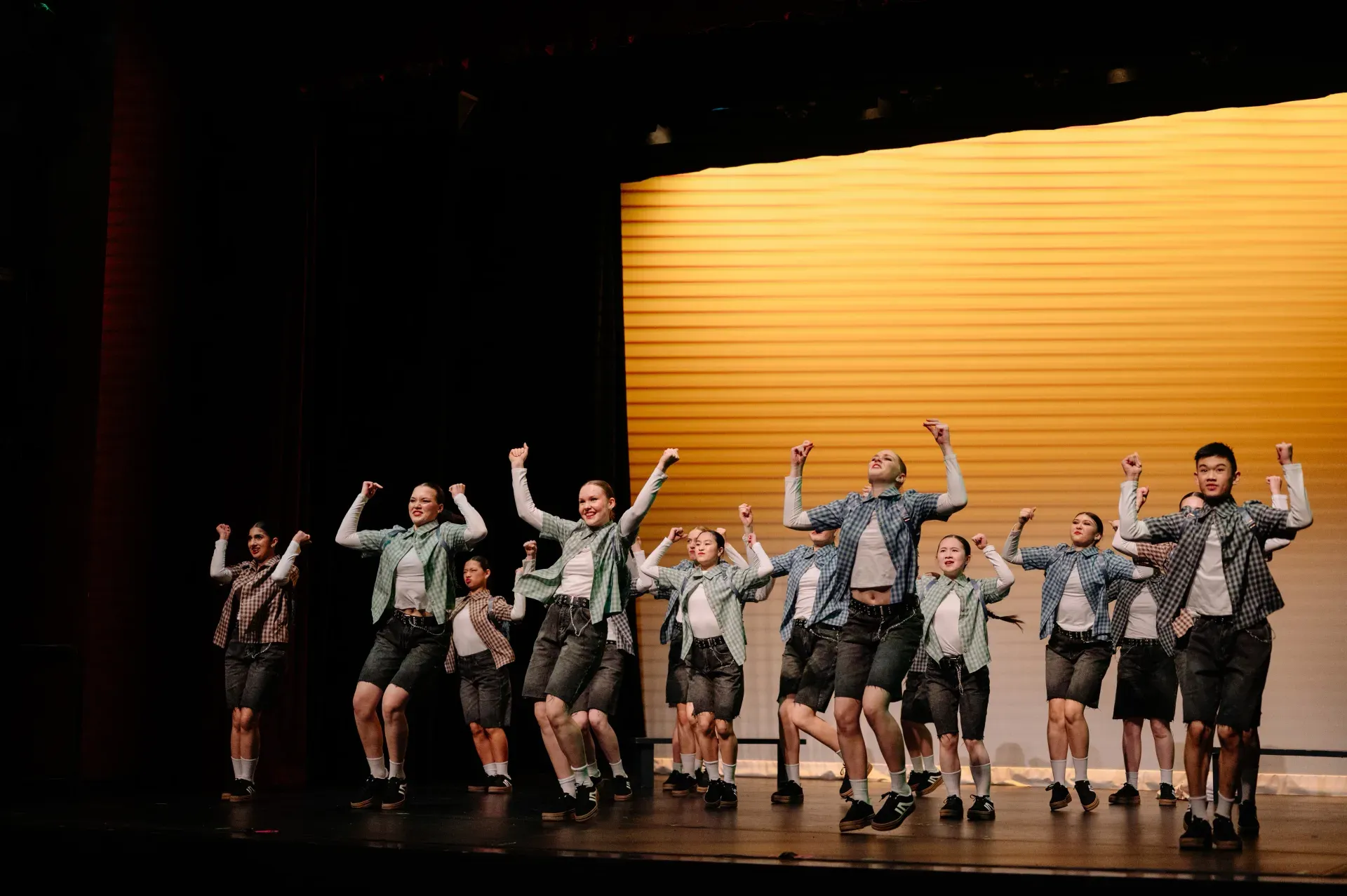 VPS Musical Theatre ensemble performing on stage, arms raised
