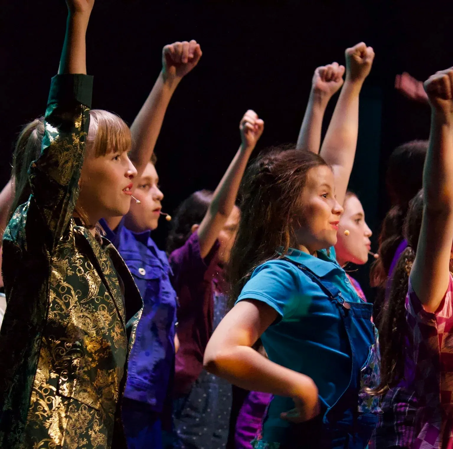 Vancouver Performing Stars performers raising fists on stage during musical theatre production